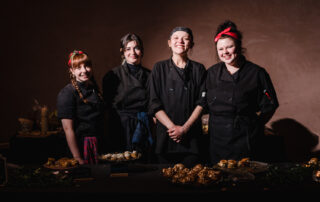 Women Wine and Food Women's Health Clinic Chefs in black outfits smiling together